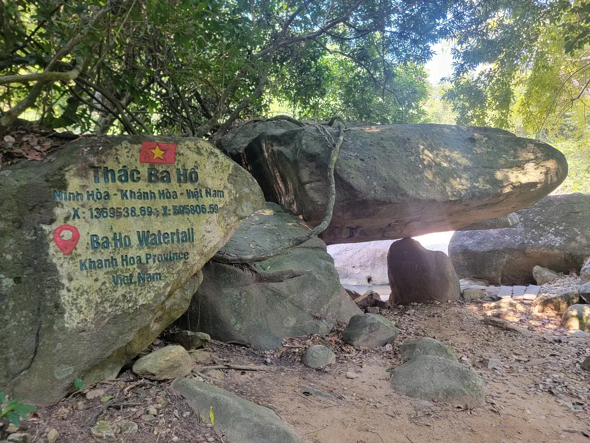 Large boulder balanced on rocks with a painted sign for the falls