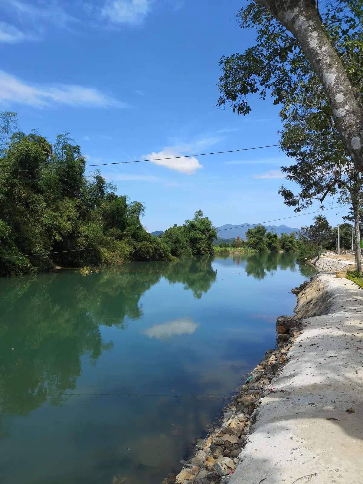 Calm river with green banks and distant hills under a blue sky