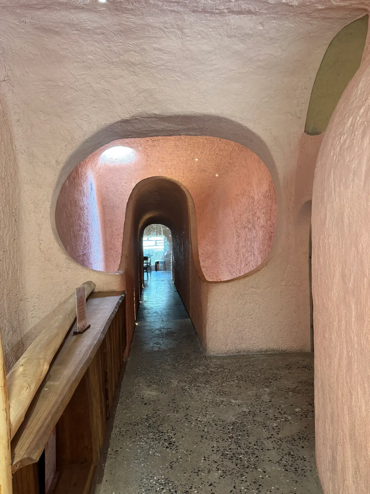 Rounded pink clay tunnel passage with an arched window opening