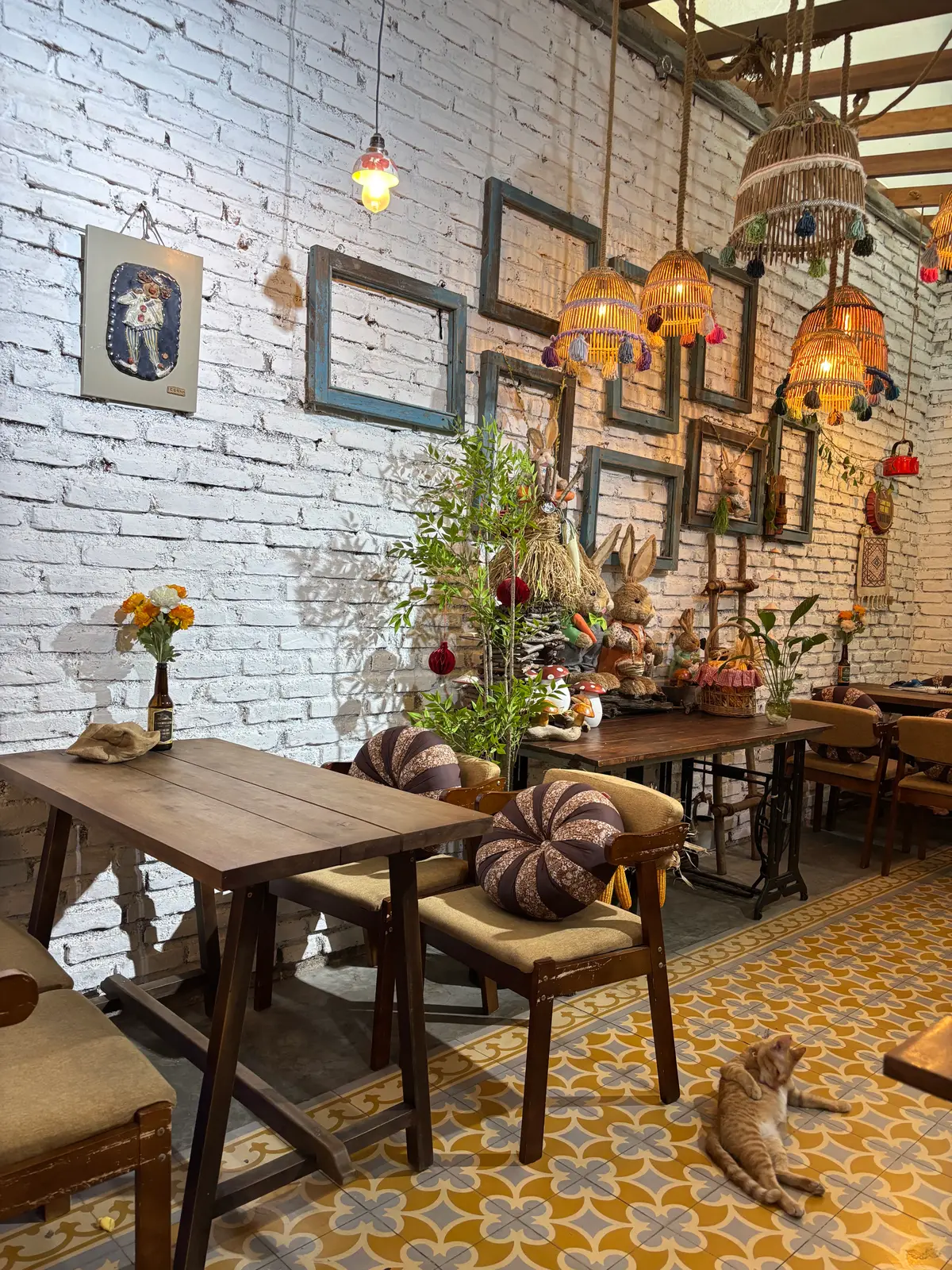 Cafe room with white brick wall, picture frames, wooden tables and cushioned chairs