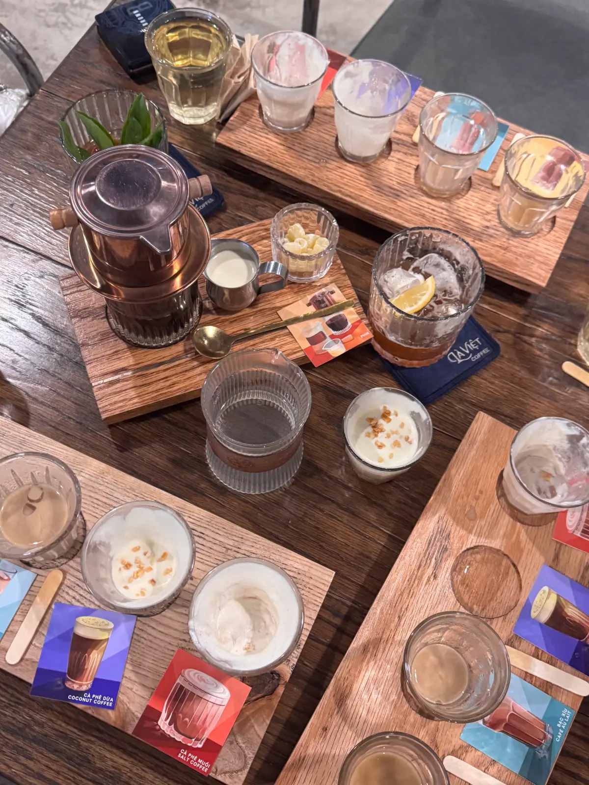 Wooden serving boards with a teapot, glasses of iced drinks and small cups of cream