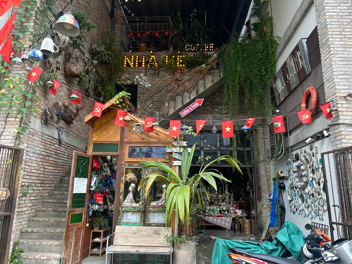 Brick alley entrance with flags, hanging plants and a wooden stall
