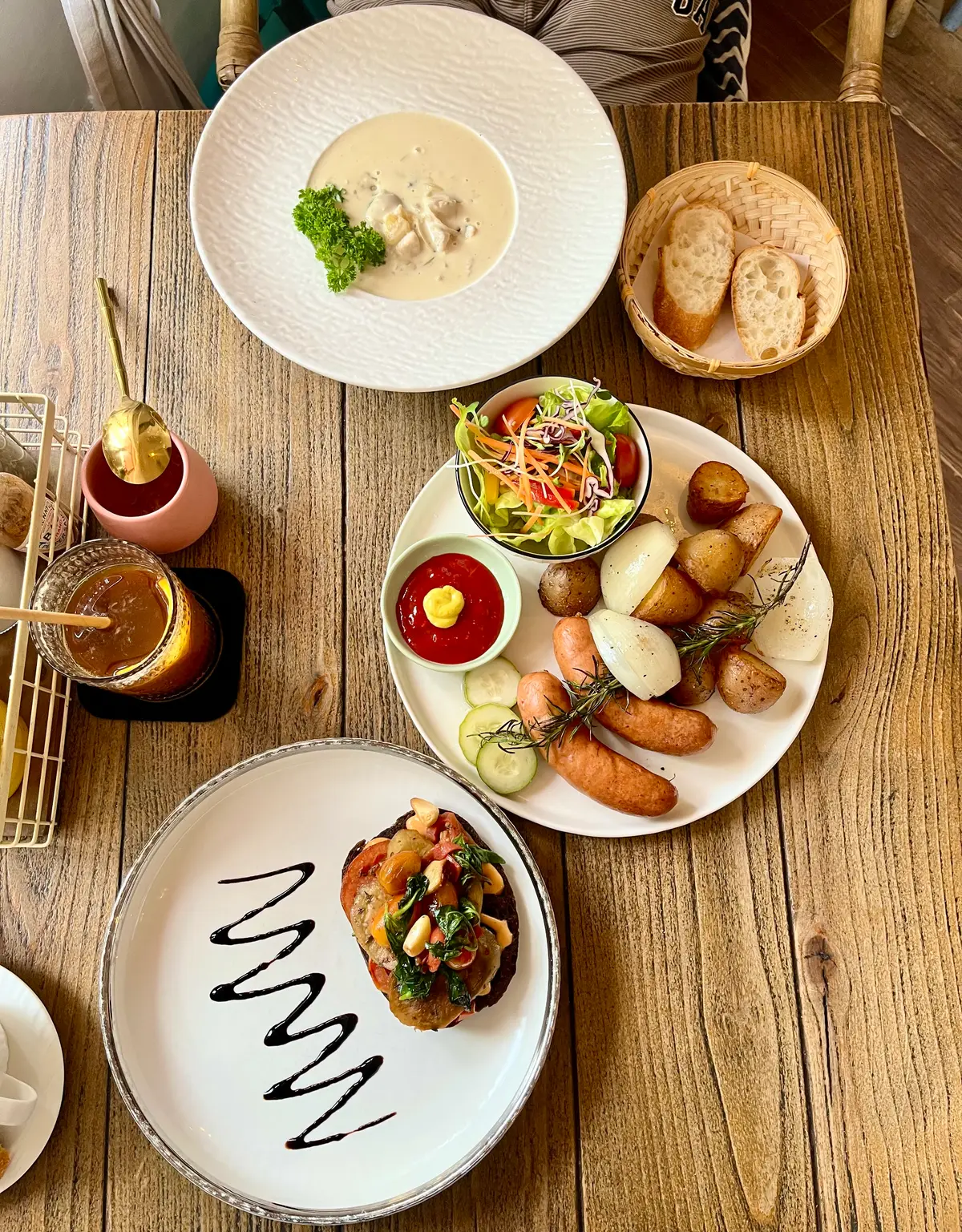 Plate of sausages, boiled potatoes and salad next to a dish and a glass of tea
