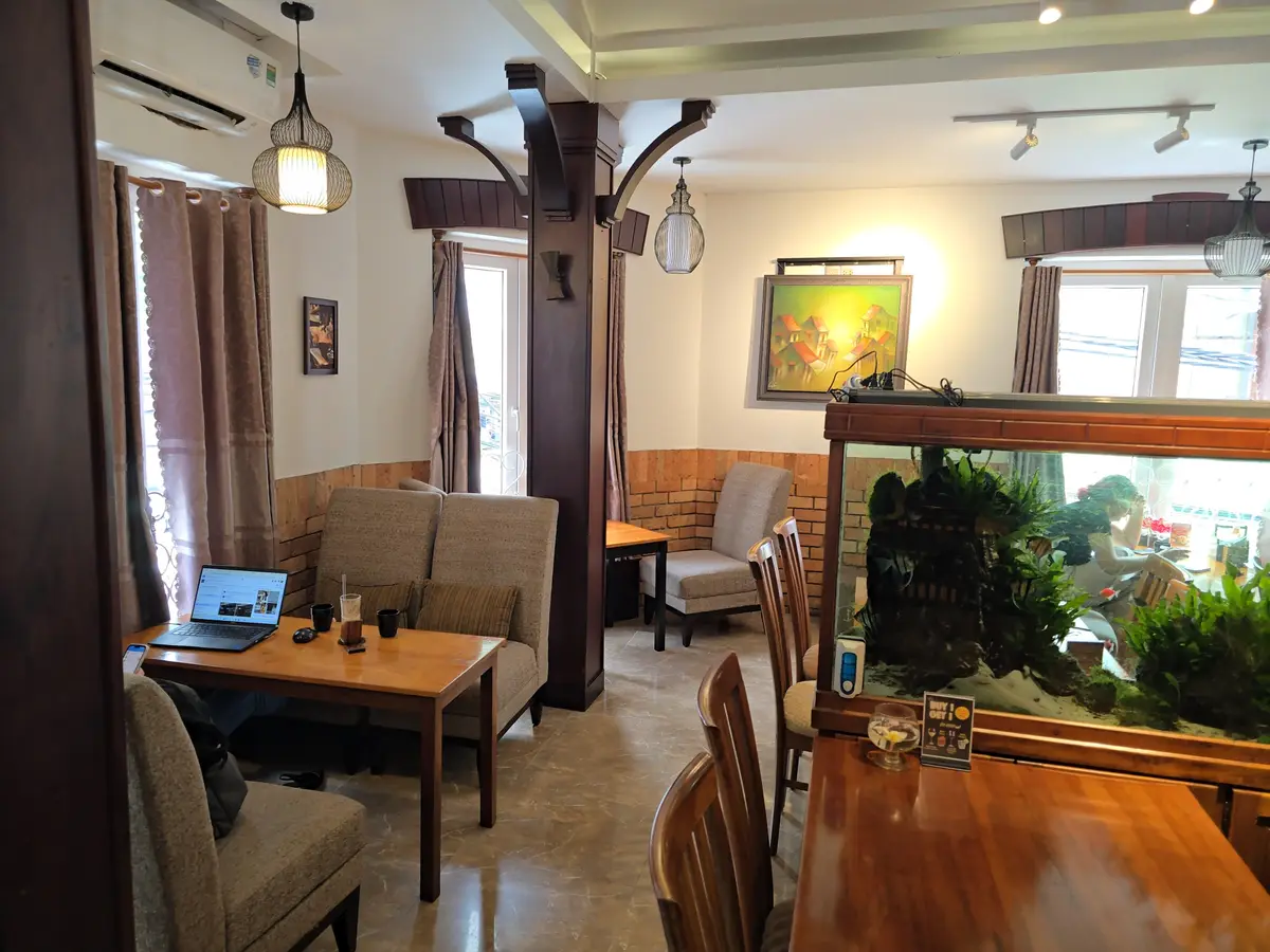 Cafe room with wooden tables, armchairs and a large fish tank by the wall
