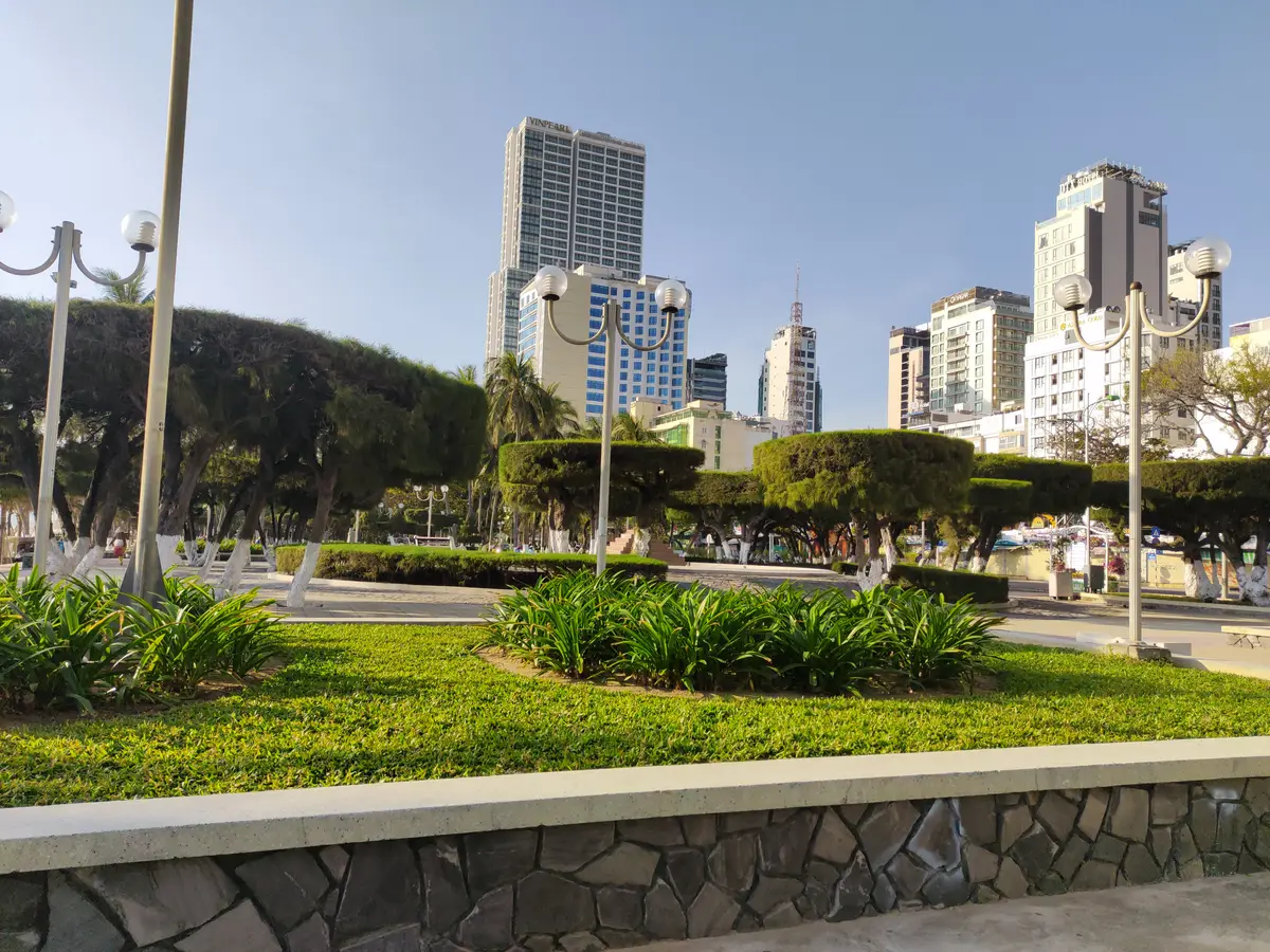 Seafront garden strip in Nha Trang with trimmed hedges, street lamps and hotel towers in the background