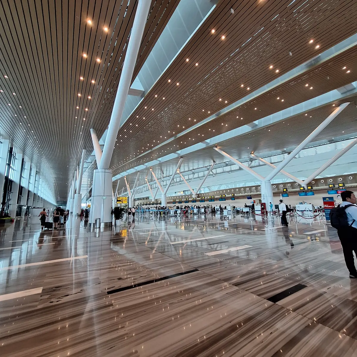 Large terminal hall with a wooden slatted ceiling and long rows of counters in the distance.