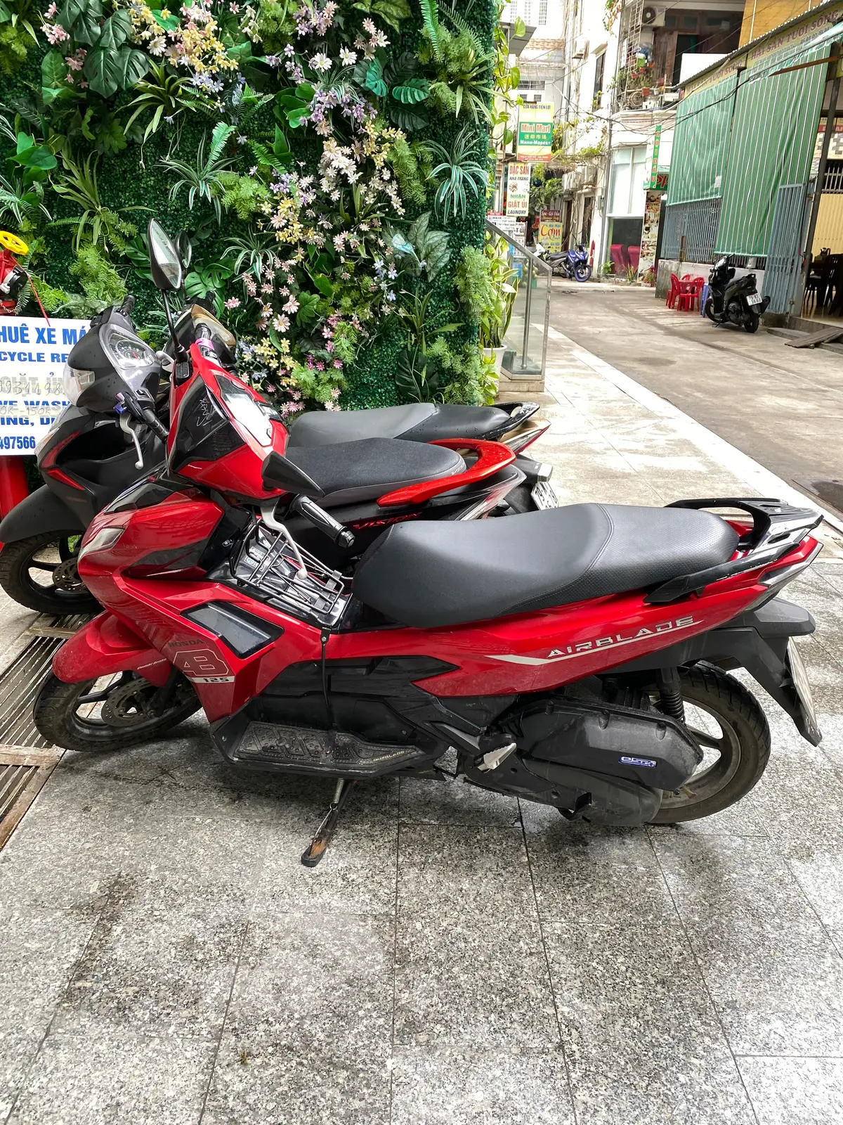 Red Honda Air Blade scooter parked on a pavement beside other scooters