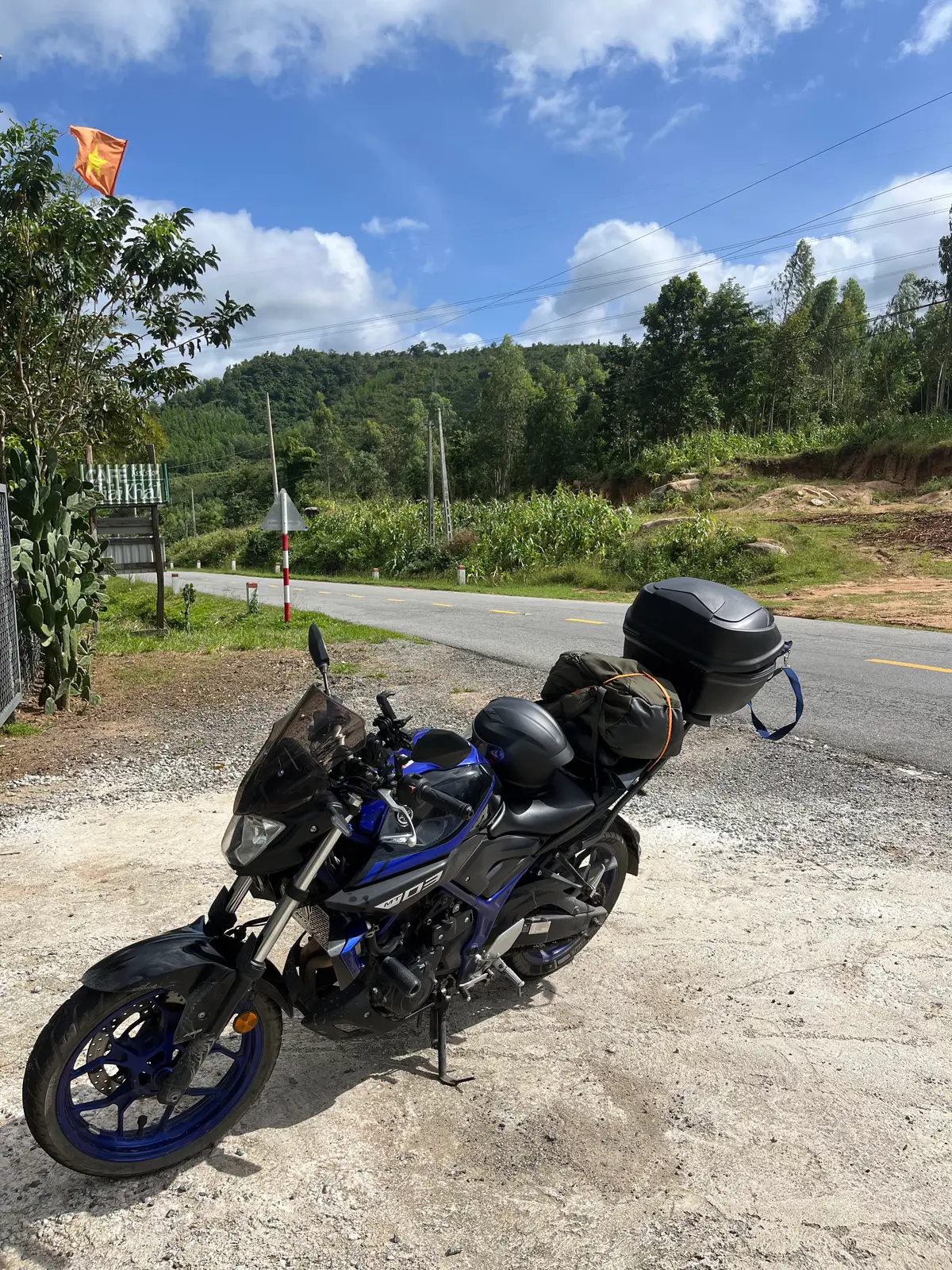 Dark blue Yamaha motorcycle with luggage parked beside a hillside road