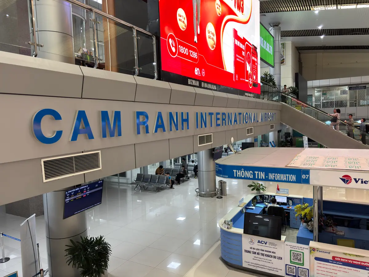 Arrival hall at Cam Ranh International Airport with the terminal name sign and an information desk.
