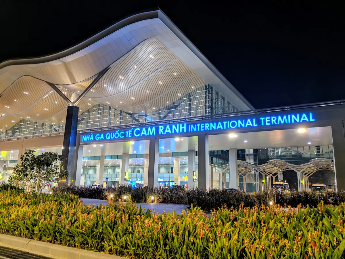 Night view of the terminal front with a glowing sign reading Cam Ranh International Terminal over a landscaped garden.