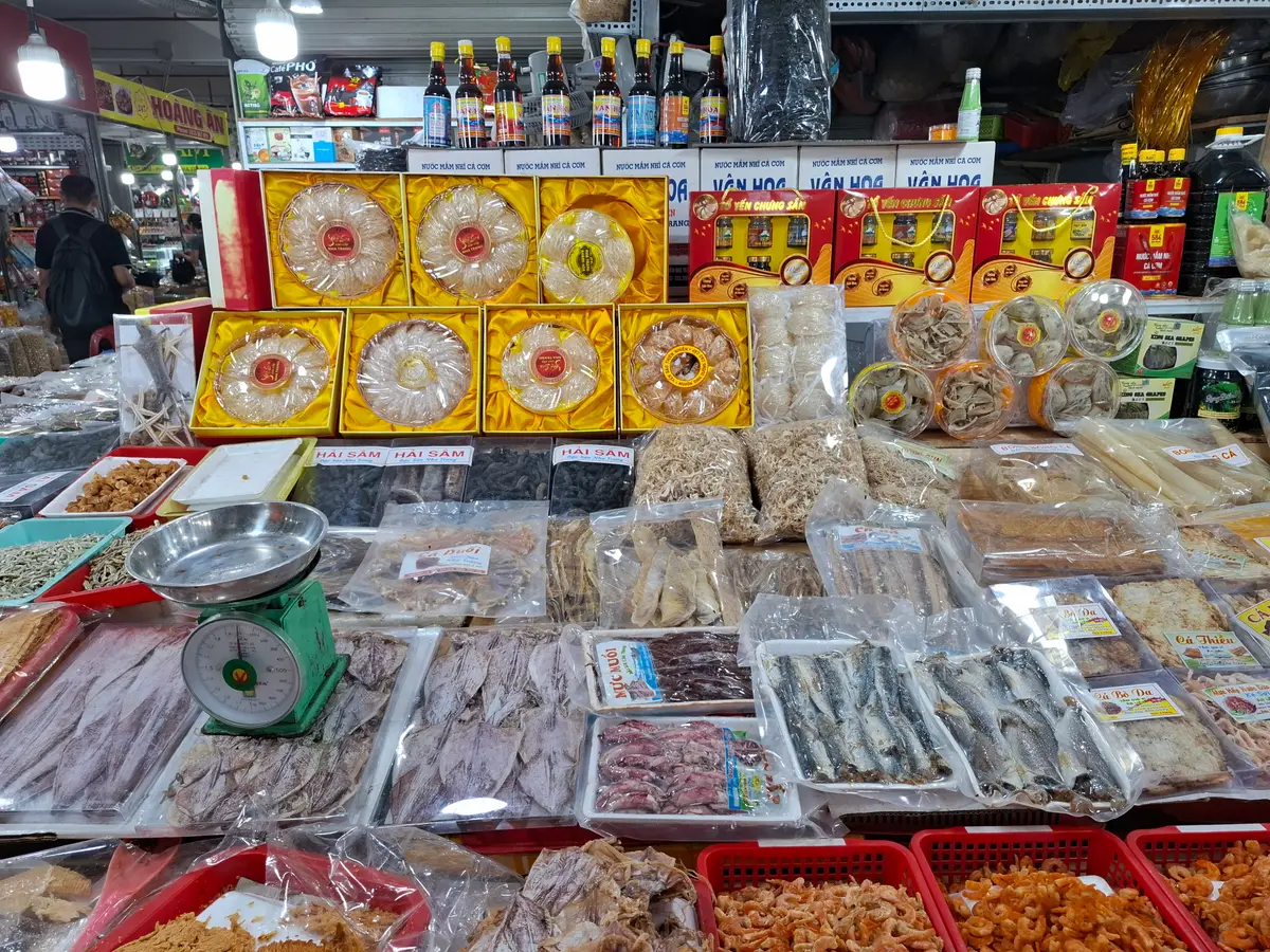 Trays of dried fish with a hand scale beside gift boxes of dried goods