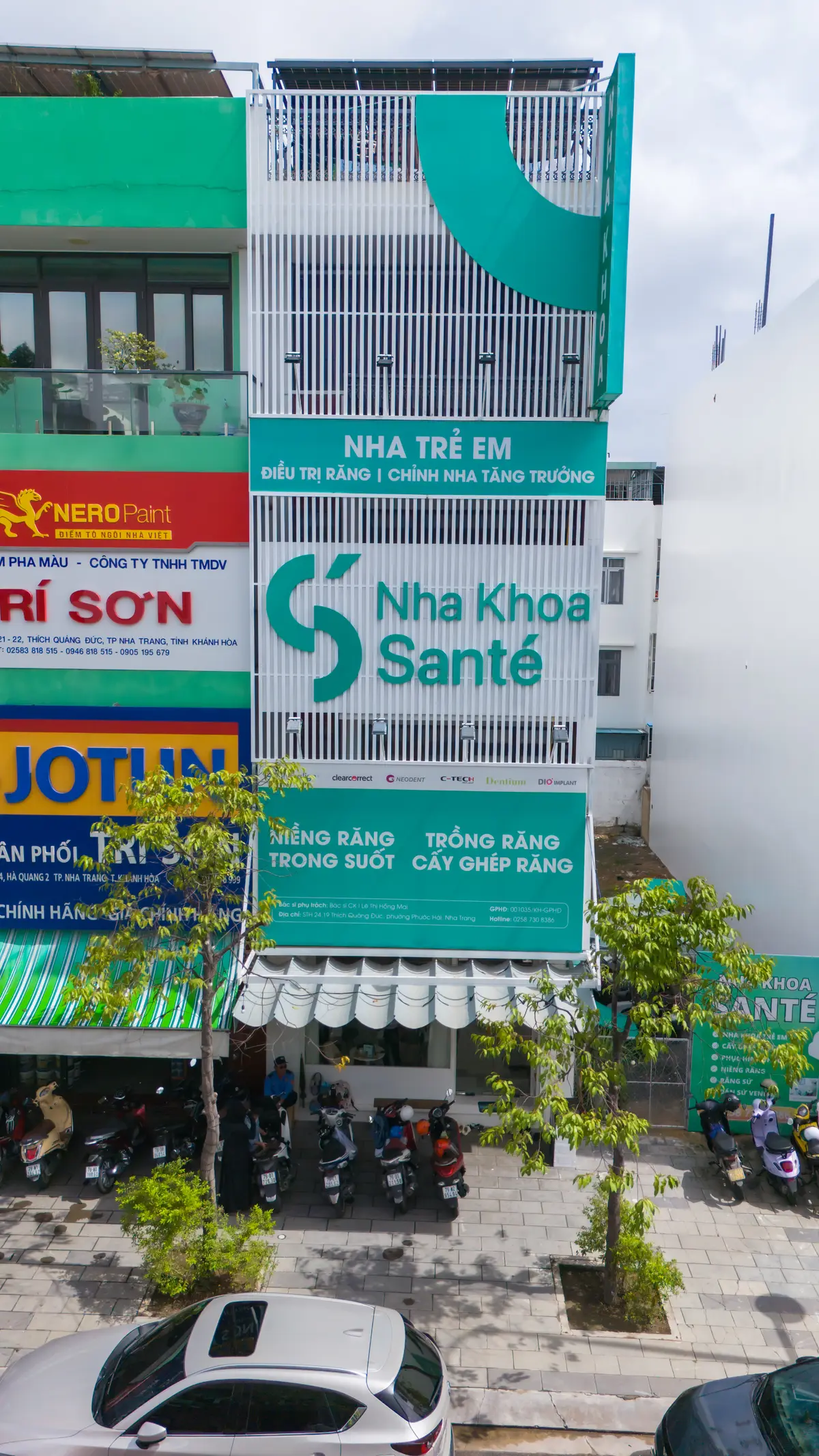 Teal and white Sante Nha Khoa shop sign with a plant in front