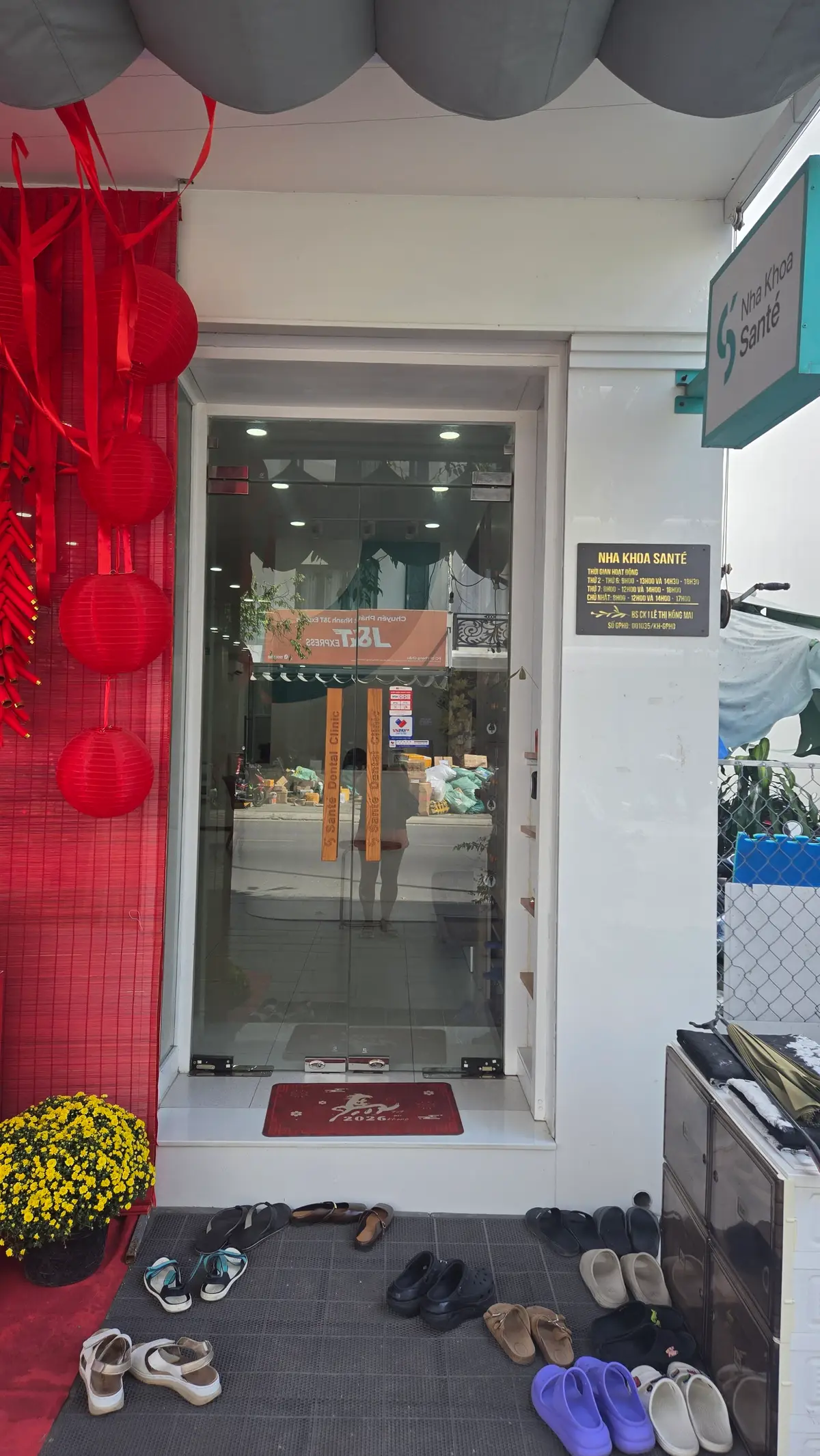 Glass entrance door of a dental clinic with red lanterns and a nameplate beside it