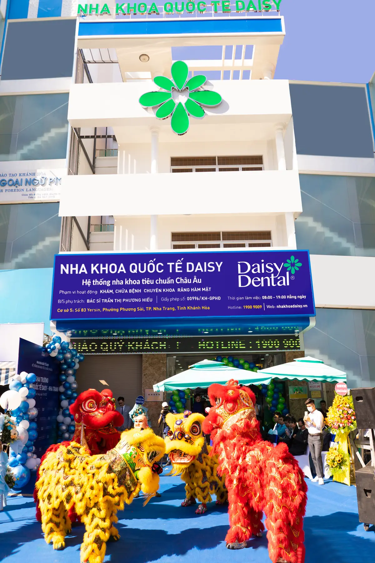 Blue DAISY dental sign above a shopfront with green umbrellas