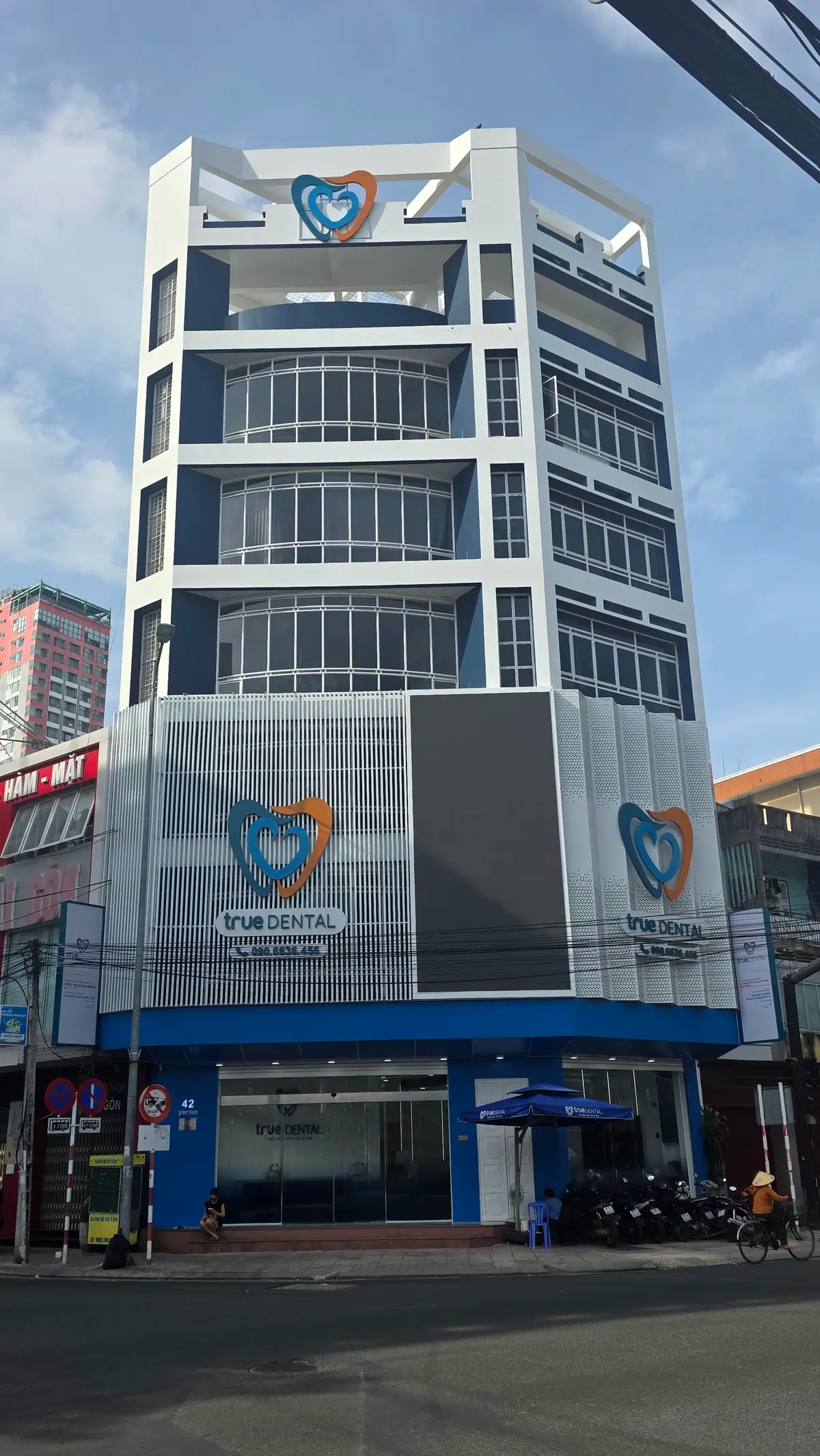 Tall glass-fronted building with a True Dental sign and logo on the facade