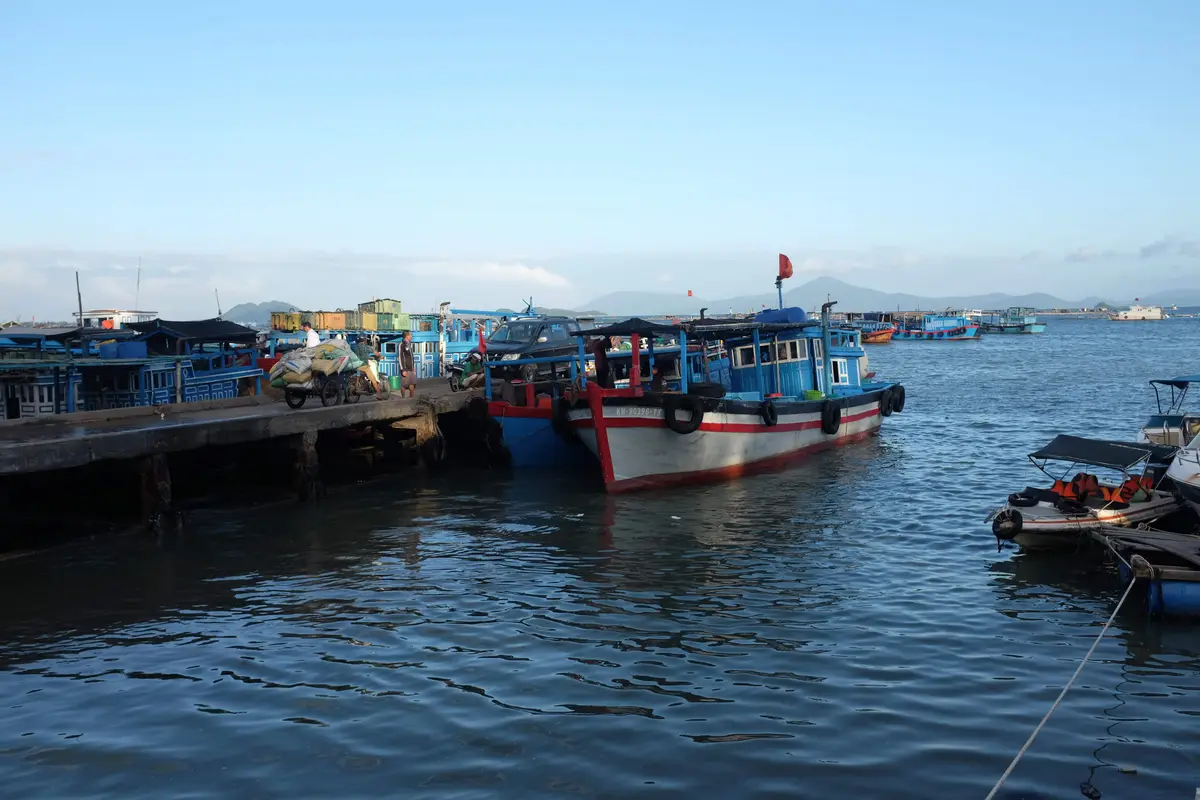 Blue and white fishing boats moored beside a wooden pier at the port