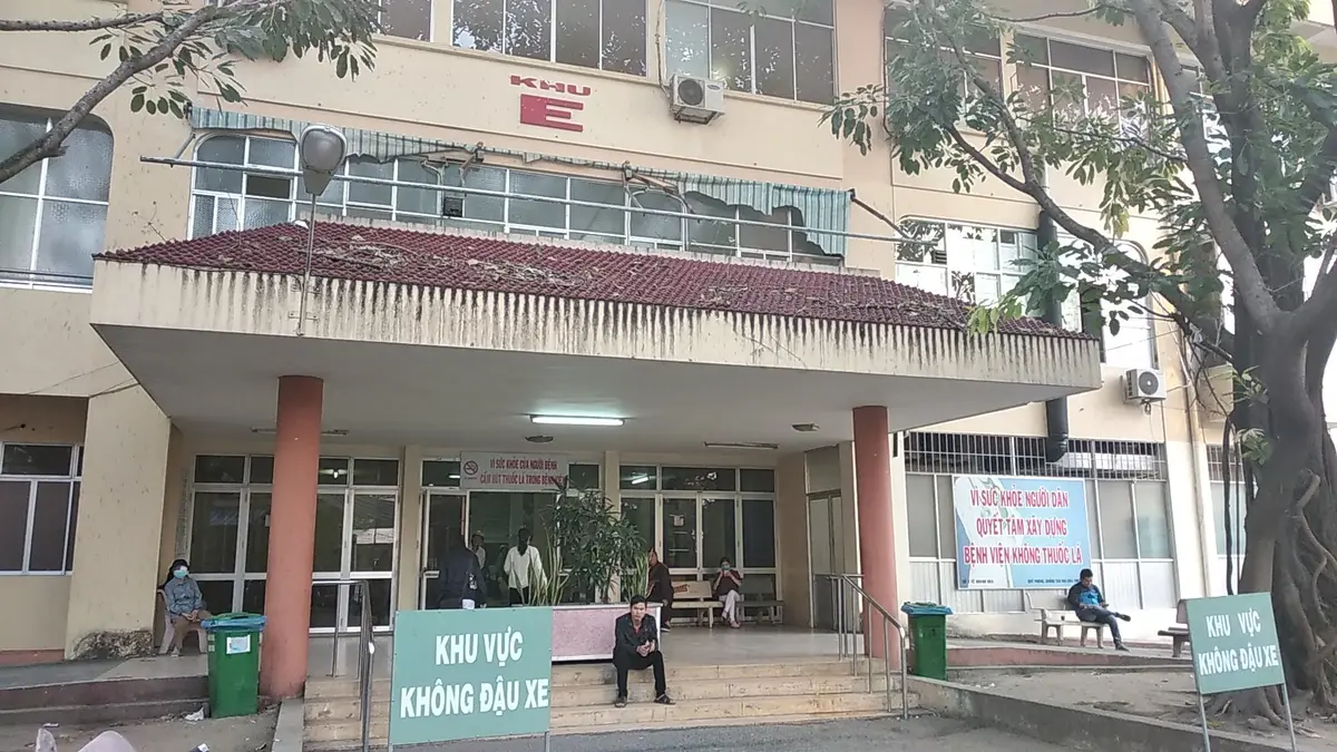 Two-storey ward building at Khanh Hoa General Hospital with a covered entrance, a no-parking sign and patients sitting outside