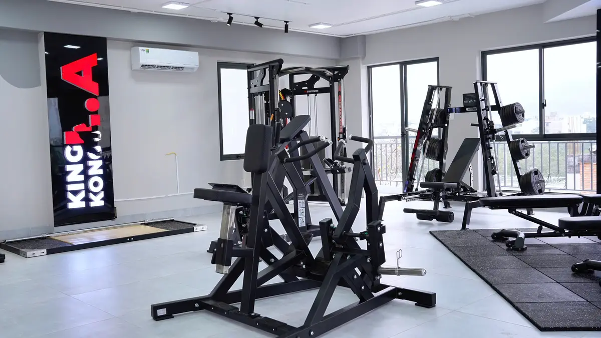 Black plate-loaded strength machine in a bright gym with large windows