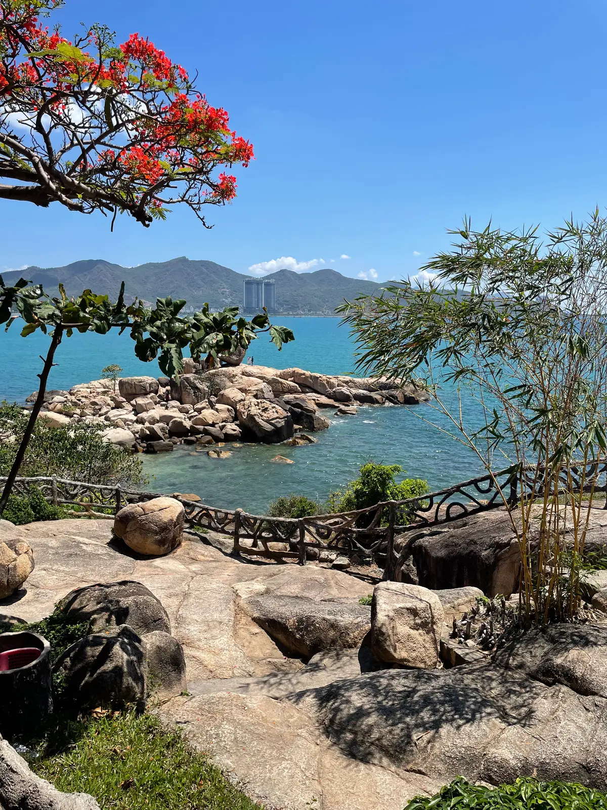 Wooden railing on a rocky path with boulders and the sea behind