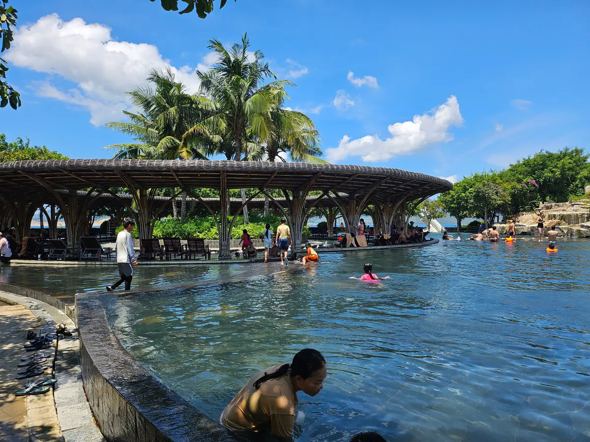 Pool beneath a wooden roof pavilion with swimmers