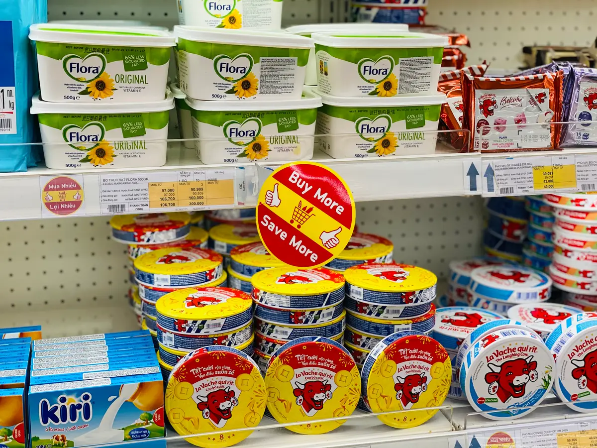 Supermarket shelf of margarine tubs, cheese portions and cream cheese in bright packaging