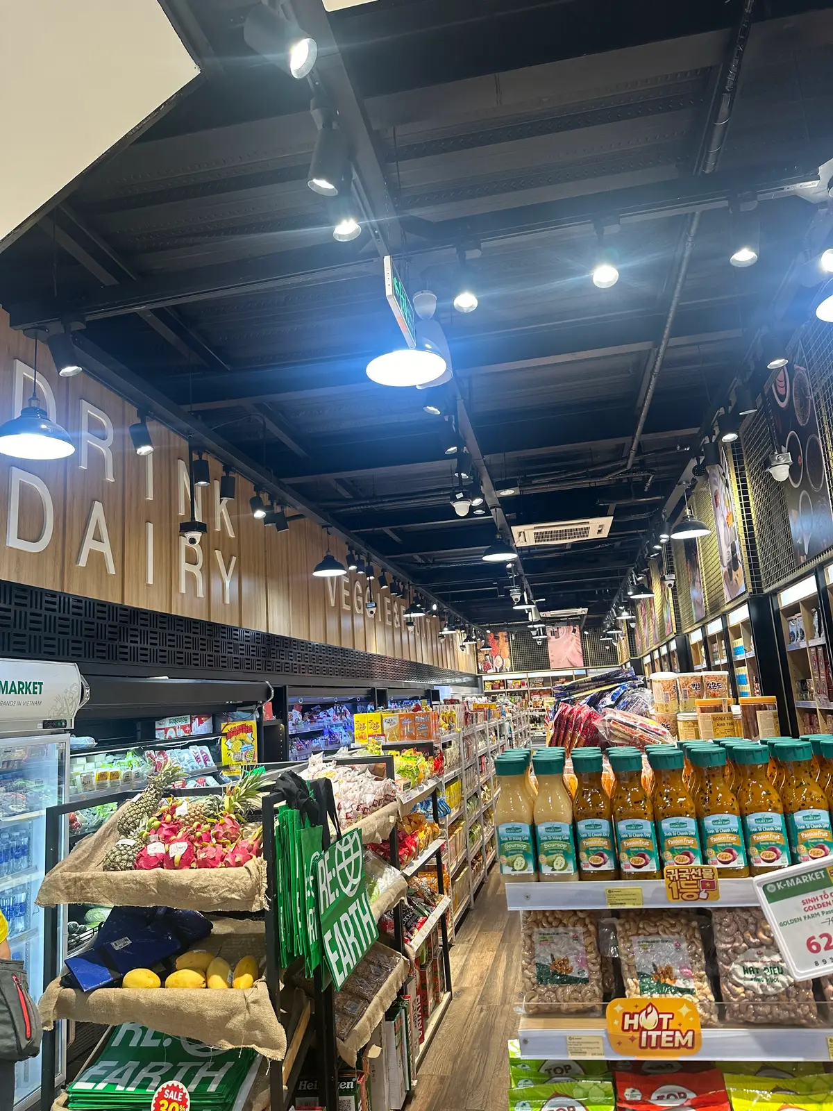 Narrow shop interior with a dairy sign above fridge shelves of drinks