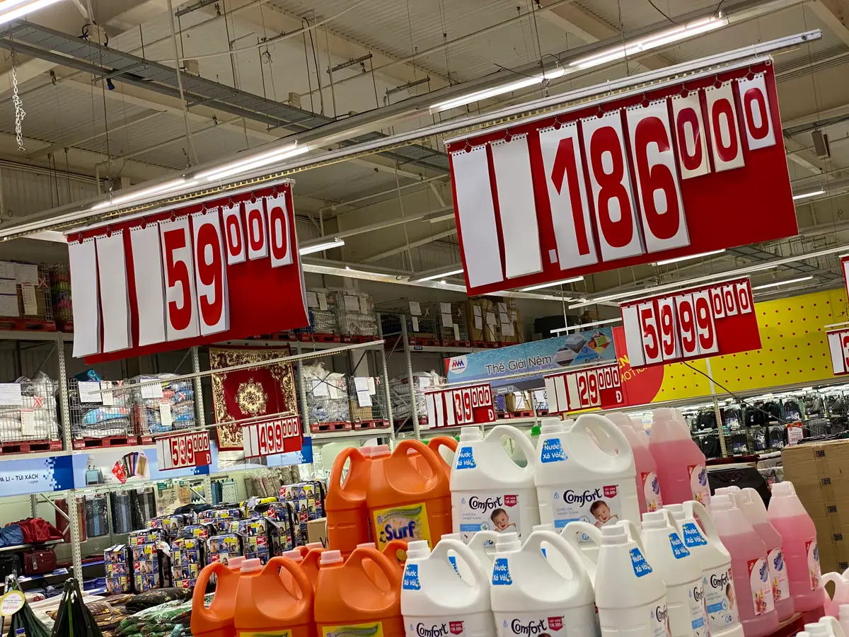 Large red price signs hanging above rows of laundry detergent bottles