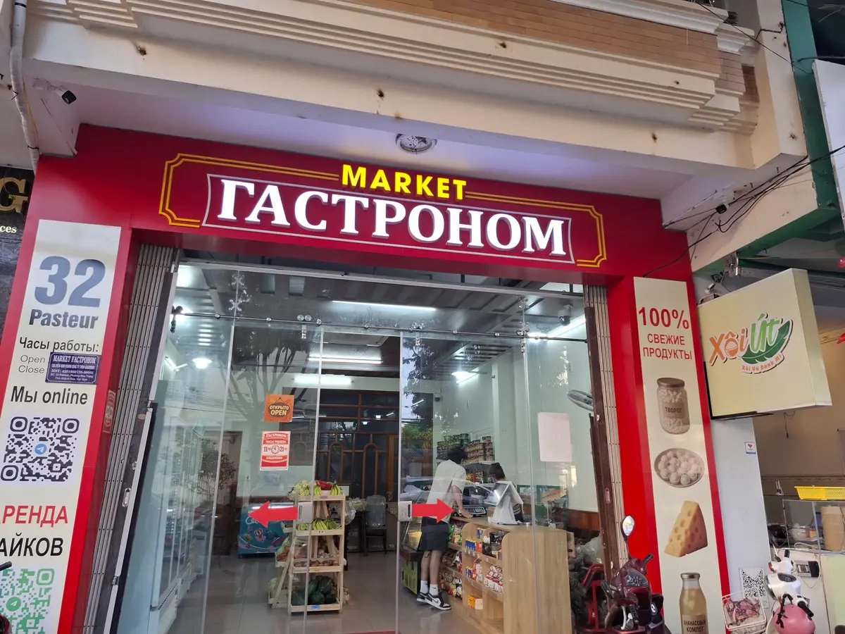 Red shop front with a Russian-language Market sign and a street sign beside the door