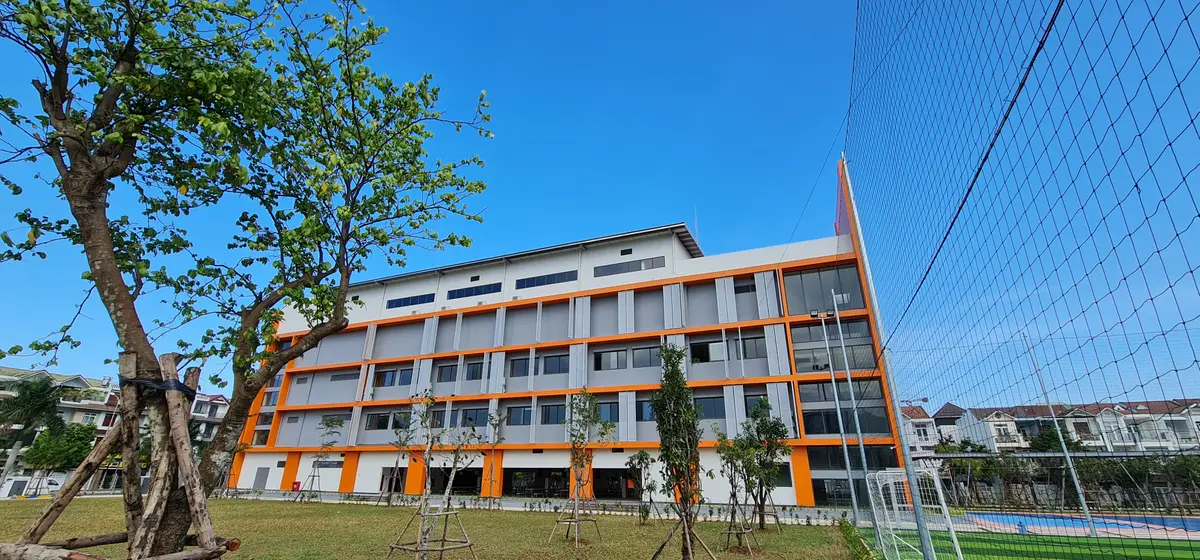 Orange and white school building with a long row of windows beside a lawn
