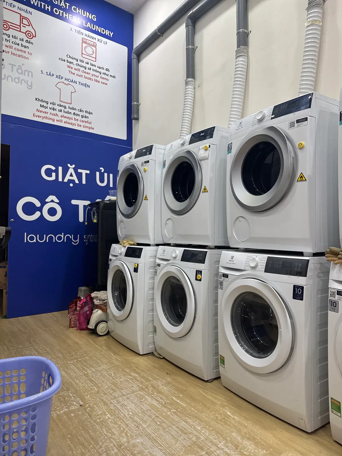 Stacked white washers and dryers against a blue wall
