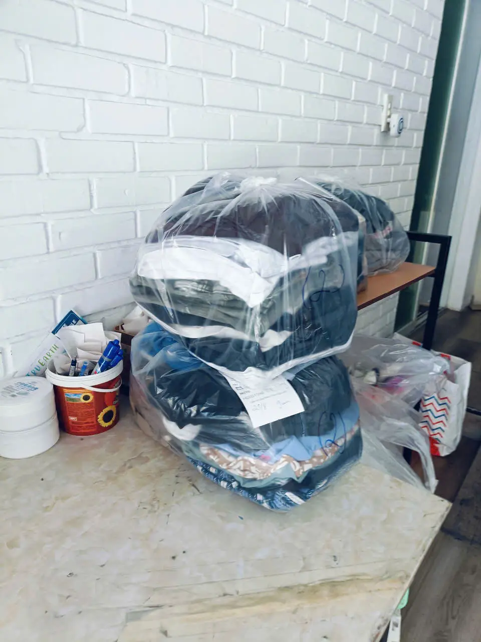 Large clear bags of laundry stacked on a bench