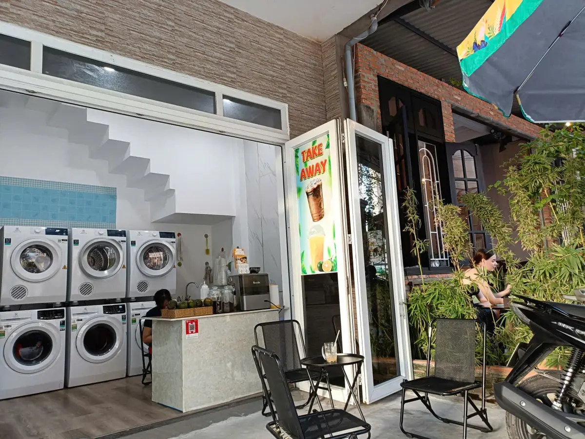 White front-loading washing machines inside a bright laundry shop with an open door