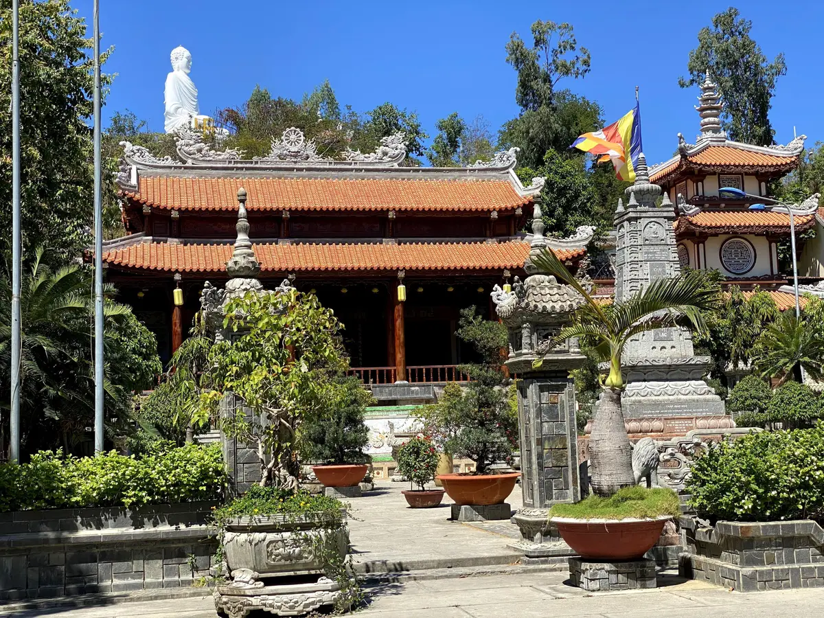 Red-roofed pagoda hall behind stone lanterns and potted plants in the courtyard