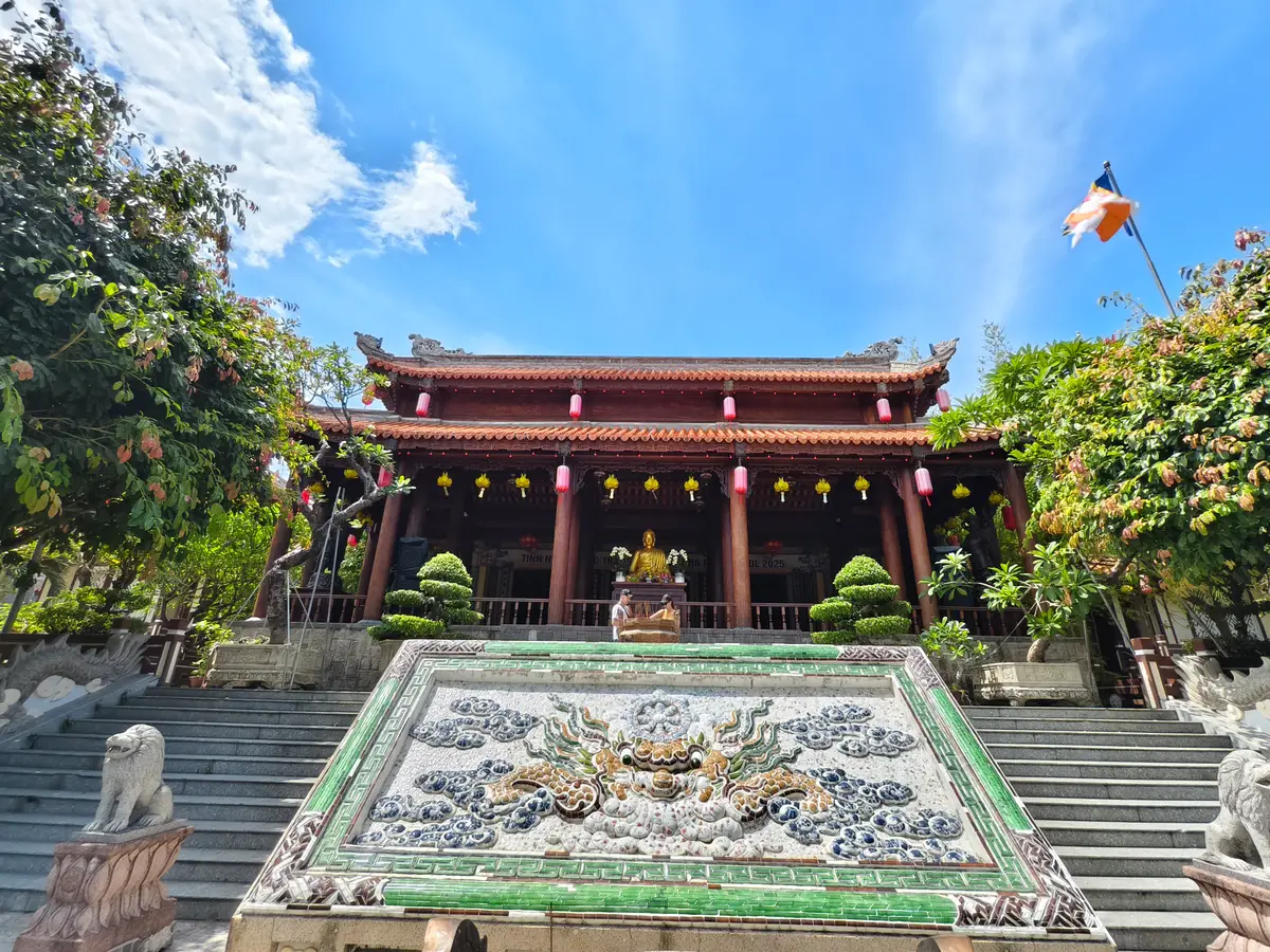 Red pillared main hall behind a ceramic dragon panel and stone steps