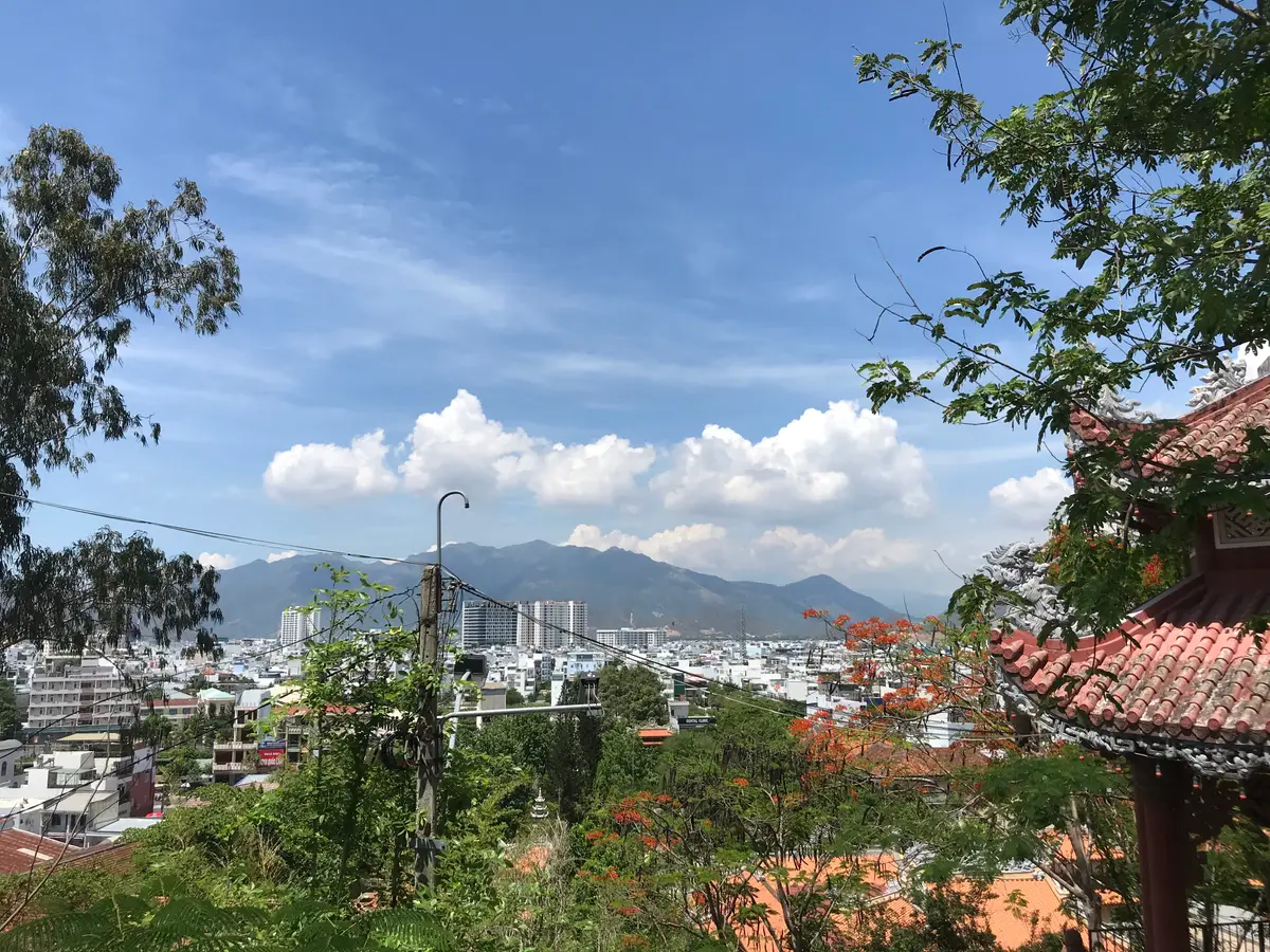 View over the city and mountains from the hillside with a red tiled roof corner