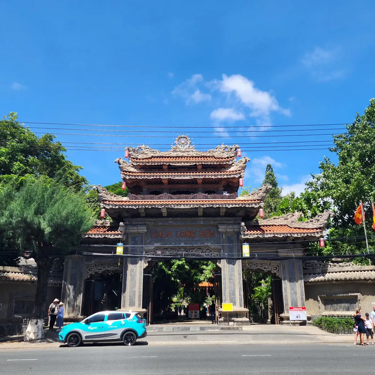 Tiled gate of the pagoda with carved roofs beside a street with a taxi