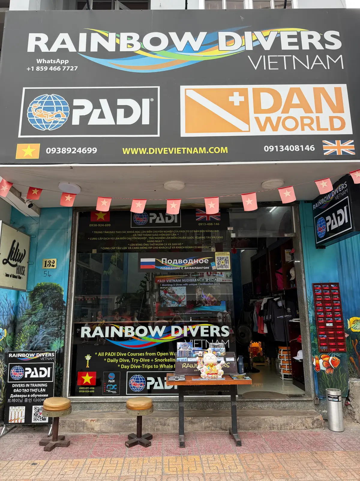 Dive shop front covered with diving certification signs, flags, fish stickers and phone numbers