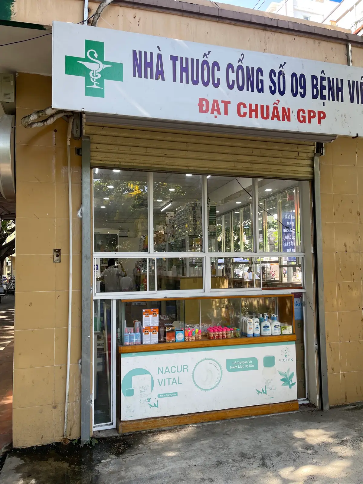 Hospital pharmacy window with shelves of medicine boxes and bottles behind glass