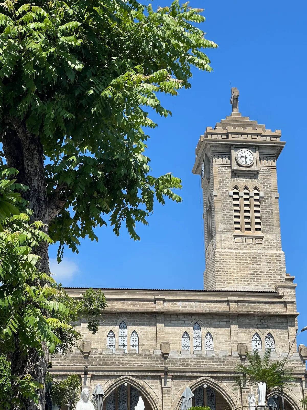 Square stone bell tower with a clock face against a blue sky