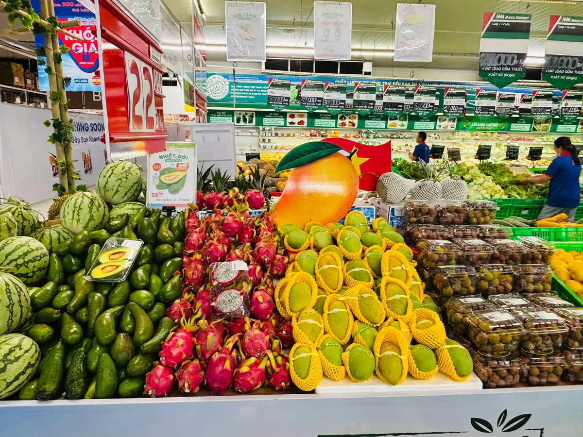 Fruit display with watermelons, dragon fruit, mangoes and boxed lychees in a supermarket