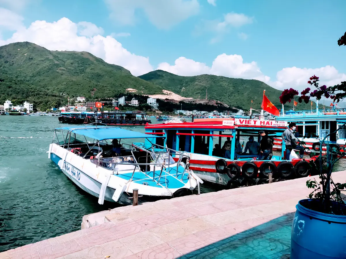 Tour boats with red and blue hulls moored along a pink paved quay