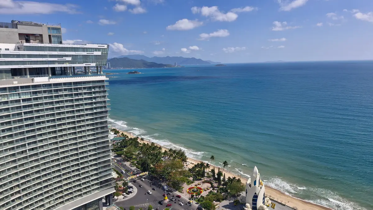 Tall apartment tower beside the sea with a long beach beyond