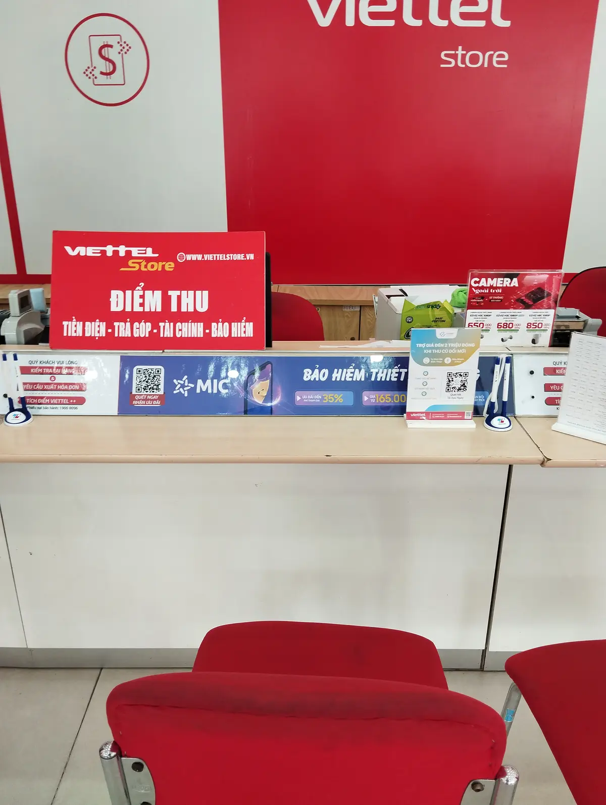 Service counter inside a mobile phone store with red stools and signs