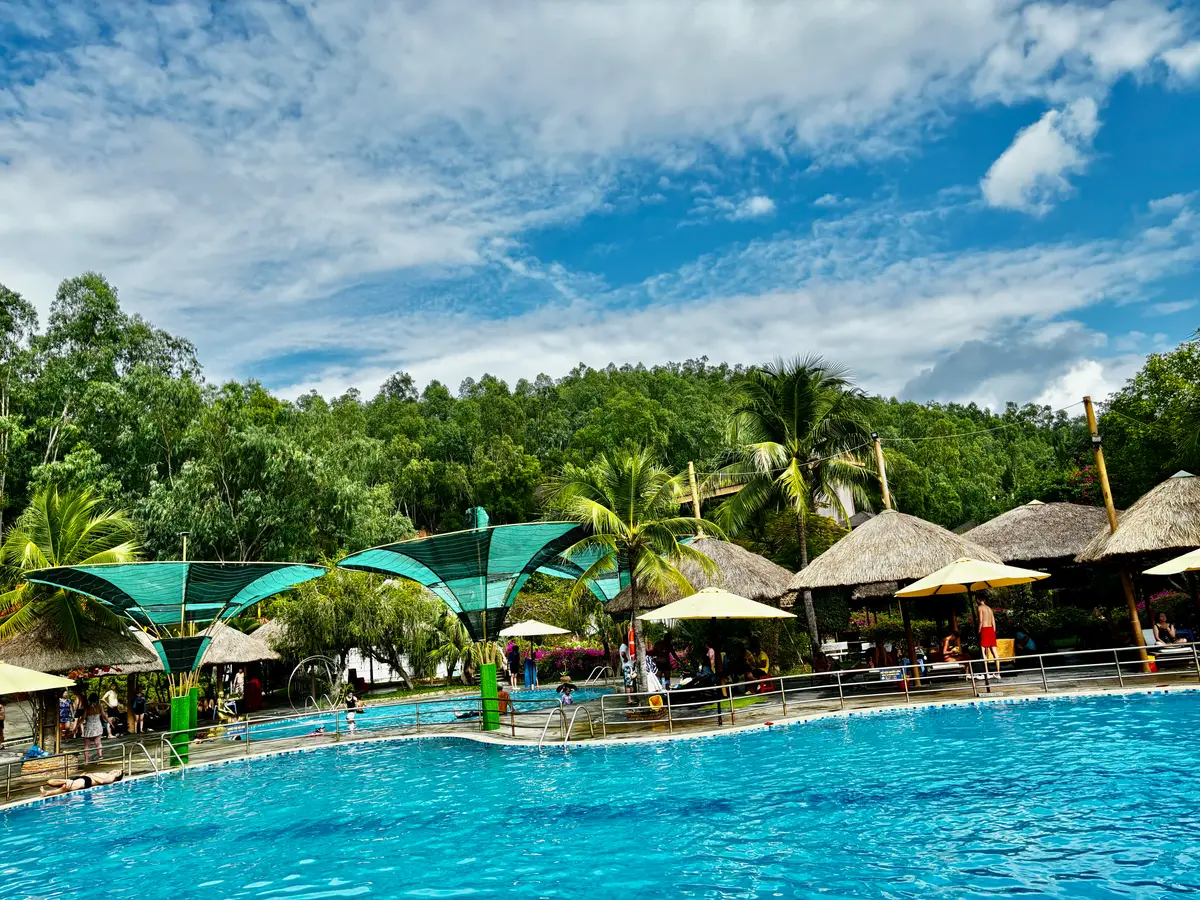 Swimming pool with straw parasols and green shade at Thap Ba hot spring