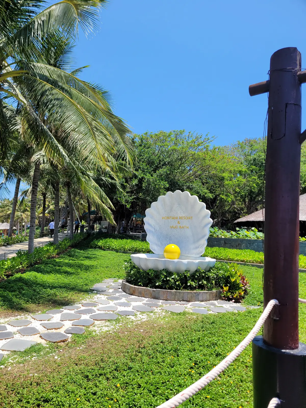White shell sculpture holding a golden pearl in a garden at Hon Tam Mud Bath