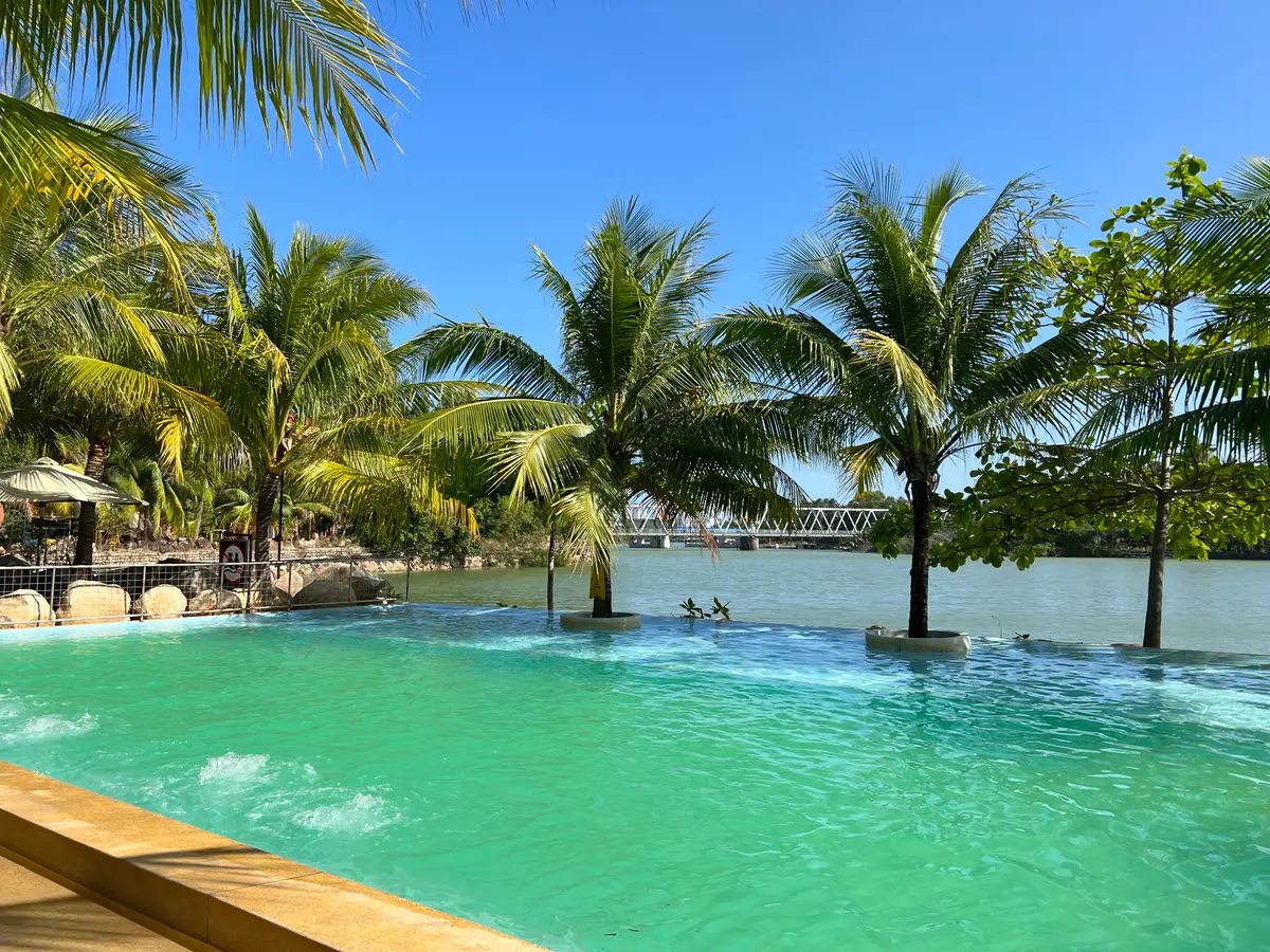Turquoise pool with palm trees along a river bank at I-Resort