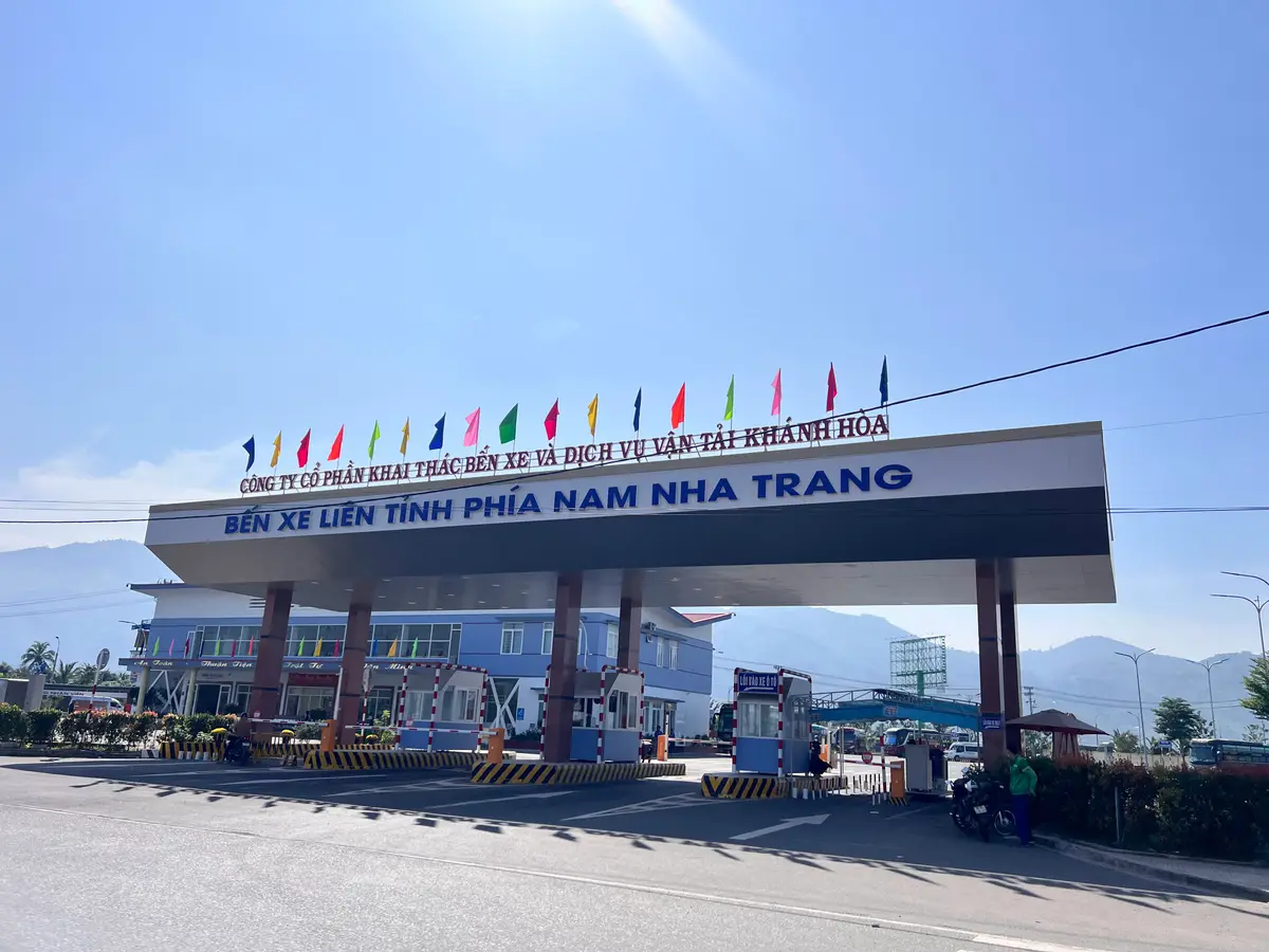 Station gate sign with a row of flags above the entrance road and mountains behind