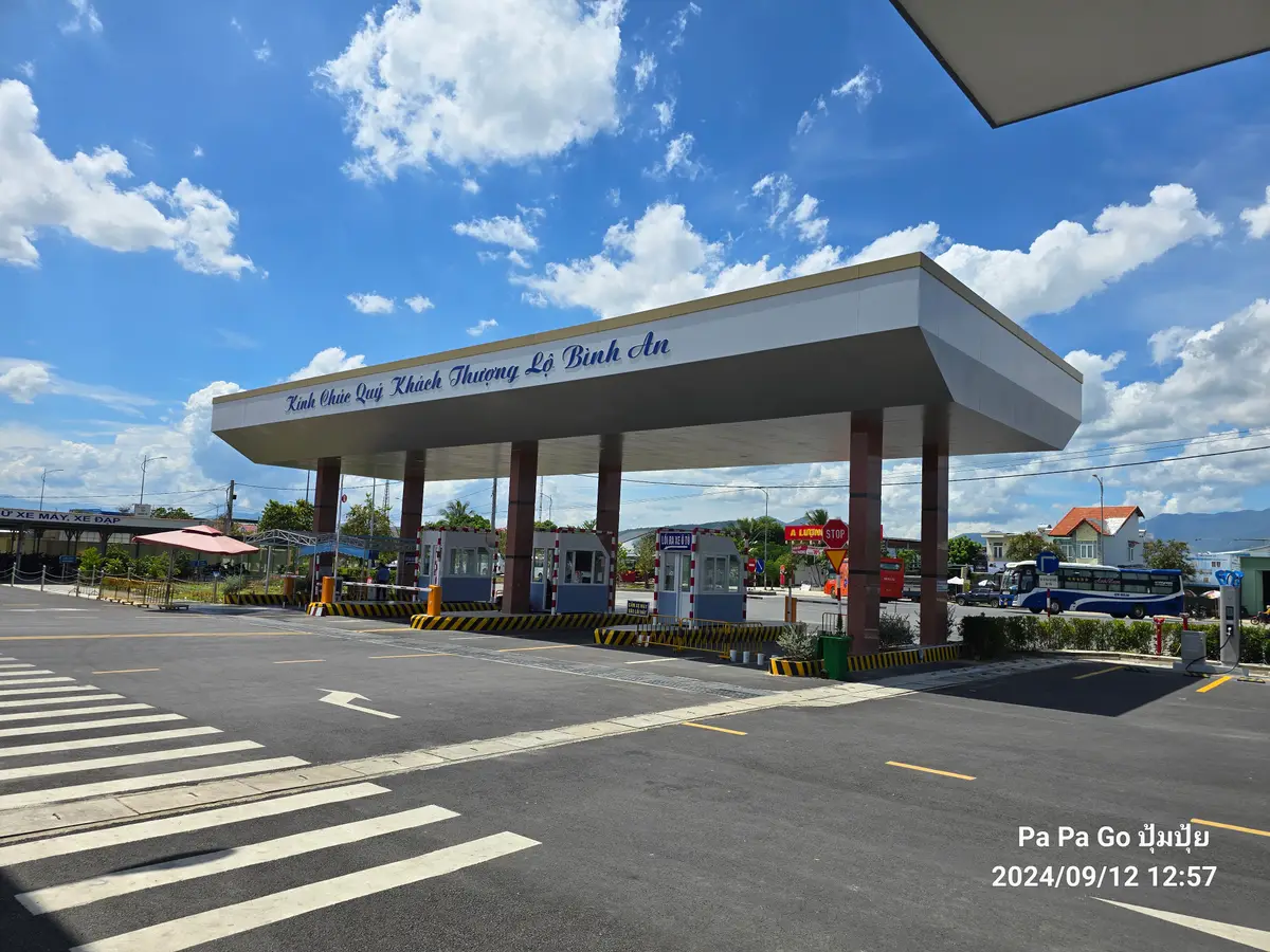 Covered entry canopy and wide empty forecourt of a modern bus station under blue sky