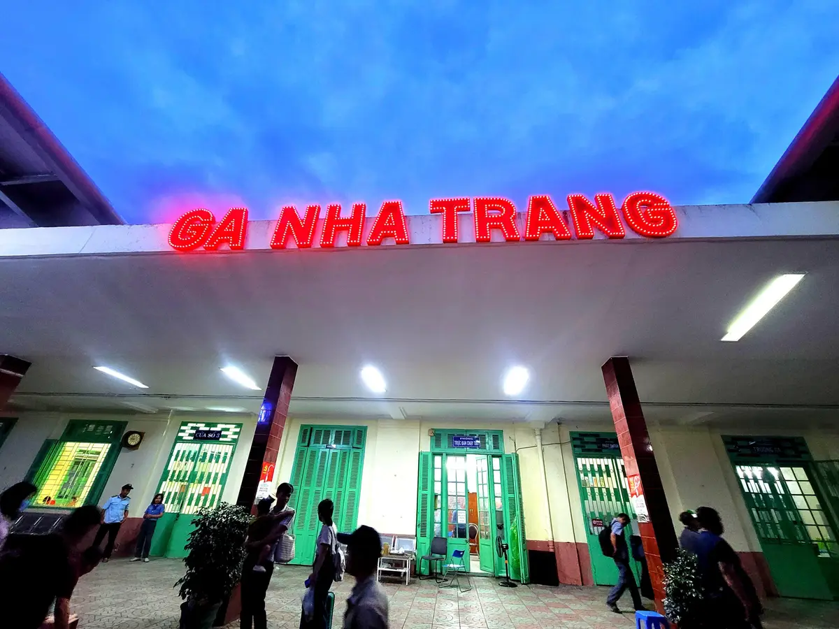 Red illuminated sign reading Ga Nha Trang above the station entrance with green doors