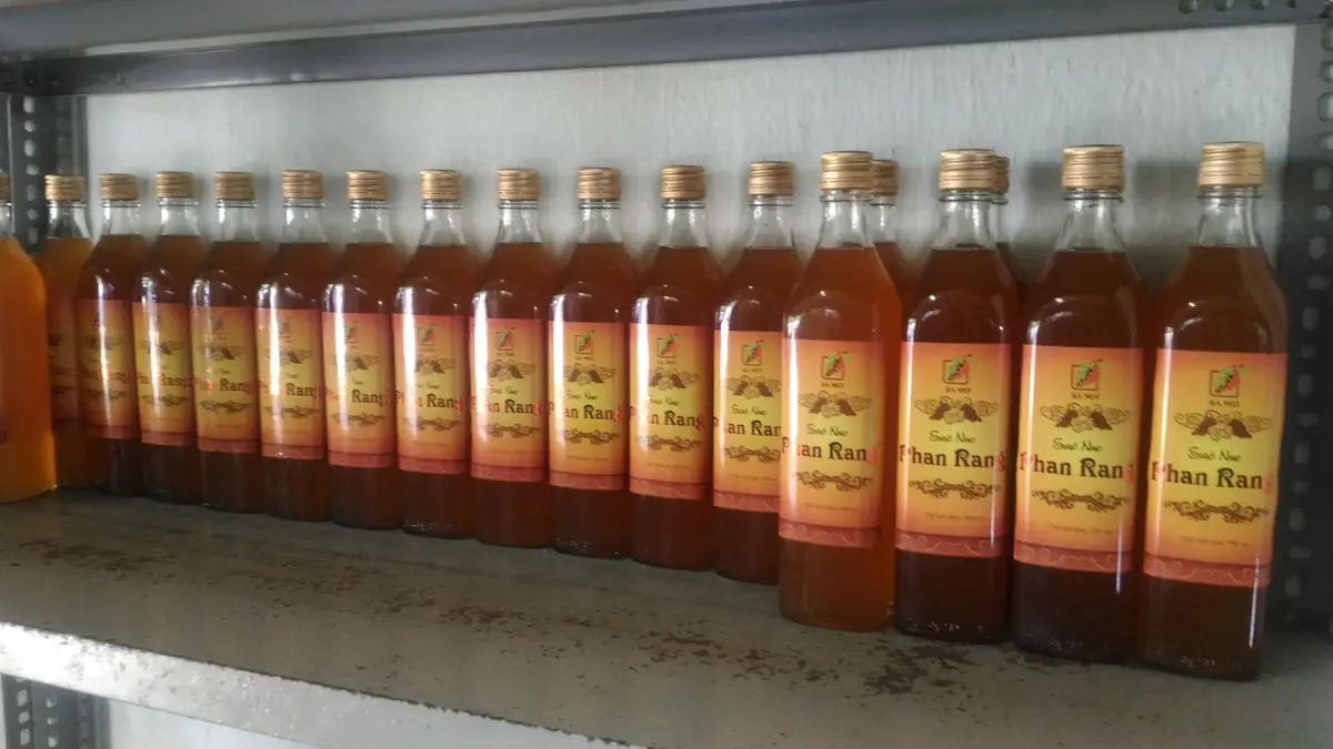 A shelf of glass bottles of amber wine with printed labels